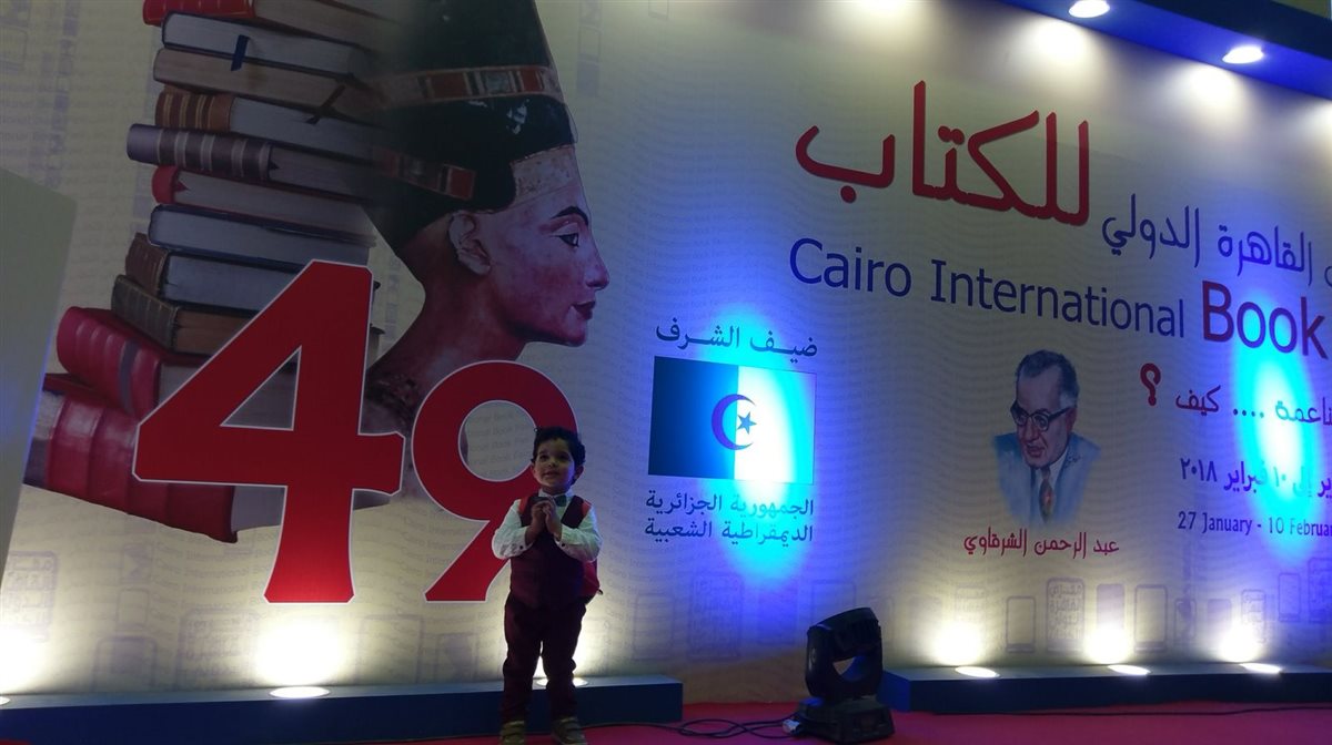أحد أبنائه خلال مشاركة والده في معرض الكتاب&nbsp;